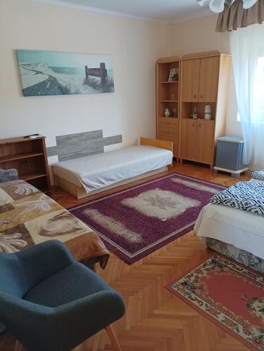a room with two beds and a chair and a rug at Bandi Vendégház in Verpelét