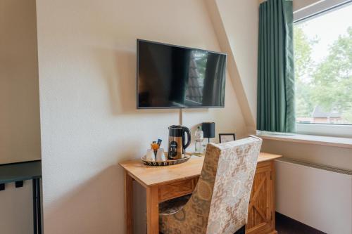 a room with a table and a television on a wall at Hotel Thesdorfer Hof in Pinneberg