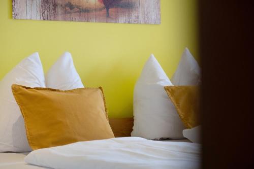 a bed with white pillows and a yellow wall at Bäuerleshütte in Breitnau