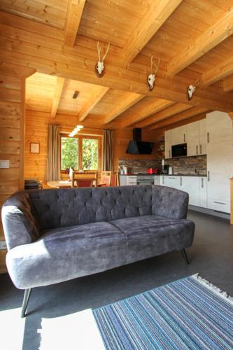 a leather couch in a living room with a kitchen at AlpenChalets Ausseerland in Bad Mitterndorf