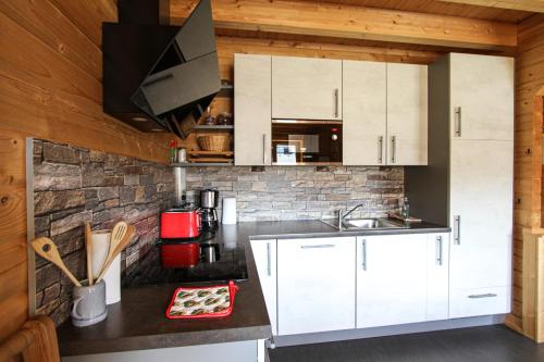 a kitchen with white cabinets and a brick wall at AlpenChalets Ausseerland in Bad Mitterndorf
