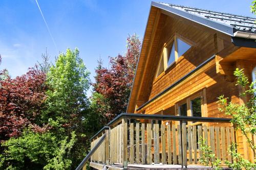 a wooden house with a balcony and trees at AlpenChalets Ausseerland in Bad Mitterndorf