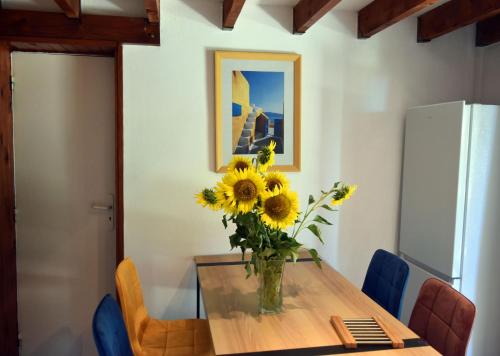 un vase de tournesols assis sur une table en bois dans l'établissement Repos et Tranquillité - Super Calme de la campagne - Clim - Grande Piscine Partagée au Sel - Déco cosy tout confort - Proche Commodités, à Montélimar