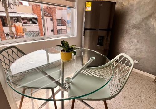 a glass table and two chairs with a potted plant at PARK 66 Apartaestudios in Cali