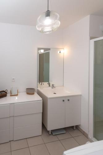 une salle de bain blanche avec un lavabo et un miroir dans l'établissement Appartement BRISE MARINE, à Labenne