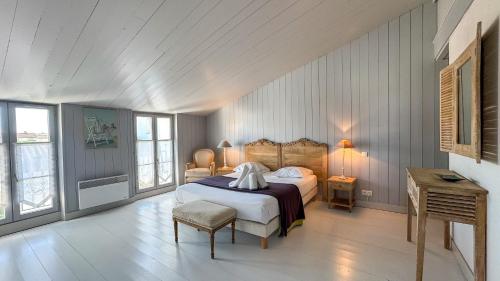 a bedroom with a bed and a table and windows at Magnifique maison de village rhétaise in Sainte-Marie-de-Ré