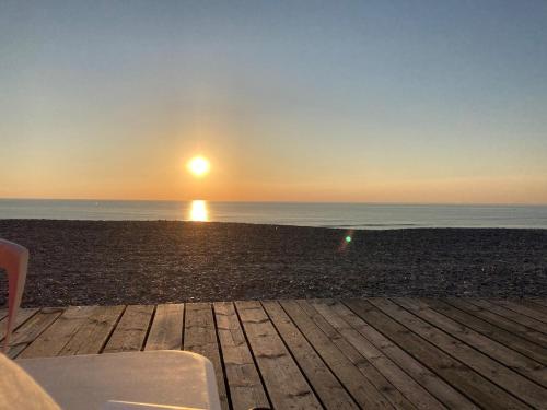a sunset over the ocean with a bench on a beach at Quiet house, Cayeux-sur-Mer, Baie de Somme in Cayeux-sur-Mer