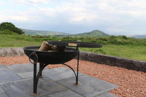 a barbecue grill with logs in it sitting on a stone slab at Long Meadow Shepherd Hut - Brecon Beacons, LD3 7TD in Tal-y-llyn