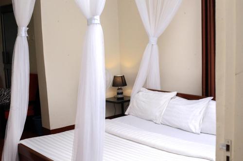 a bedroom with two beds with white curtains at Gold Palm Hotel in Gulu