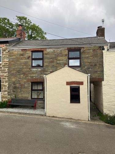 a white building with a bench in front of it at Knockers Retreat, St Agnes in St. Agnes