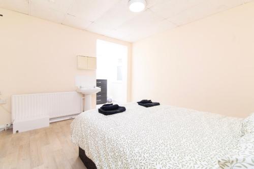 a white bedroom with a bed with black towels on it at Brookvale Road Guest House Room 7 in Southampton