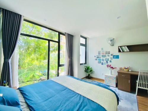 a bedroom with a blue bed and a large window at Pina Home in Da Nang