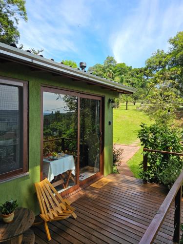 a green house with a wooden deck with a table at Recanto Vista Verde in Nova Petrópolis