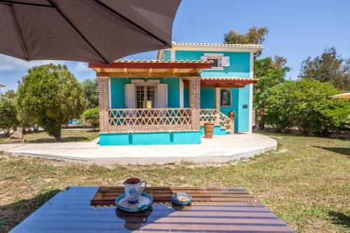 a blue house with a table and an umbrella at Porto Gerakas Villas in Vasilikos