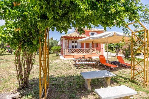 a house with chairs and a table and an umbrella at Porto Gerakas Villas in Vasilikos