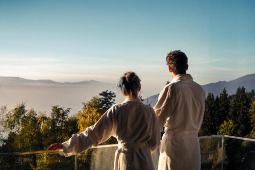 a man and a woman standing on a balcony looking at the mountains at Brandlalm Chalets in Gundisch