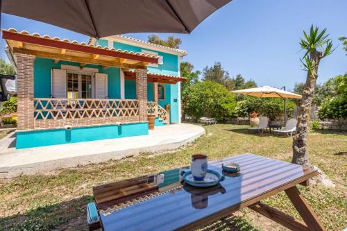 a blue house with a table and an umbrella at Porto Gerakas Villas in Vasilikos