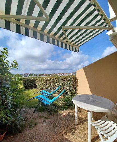un patio avec une table, des chaises et un parasol dans l'établissement Les Alizés, à Mimizan