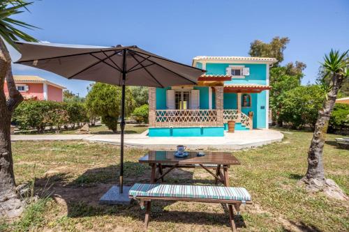 a table and an umbrella in front of a house at Porto Gerakas Villas in Vasilikos