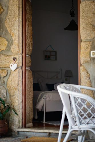 a view of a bedroom with a bed and a white chair at Casa dos Laceiras in Sandim