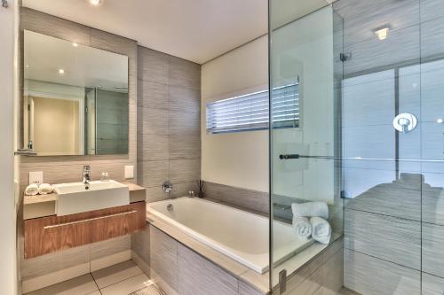 a bathroom with a tub and a sink and a mirror at Harbour Bridge Apartment on Waterfront Canal in Cape Town