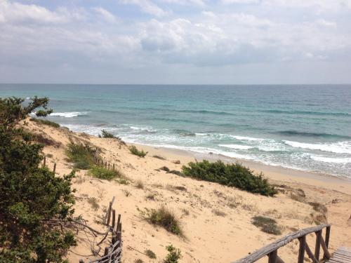 a sandy beach with a fence and the ocean at Gelsomoro beach house in Campomarino