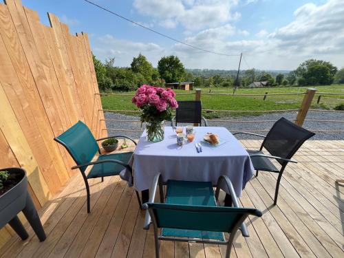 une table avec un vase de fleurs sur une terrasse dans l'établissement Les petites maisons dans la monterie - Le Jardin -, à Saint Lo