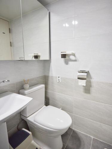 a white bathroom with a toilet and a sink at Stay Hankan 모던코리아라이프 in Seoul