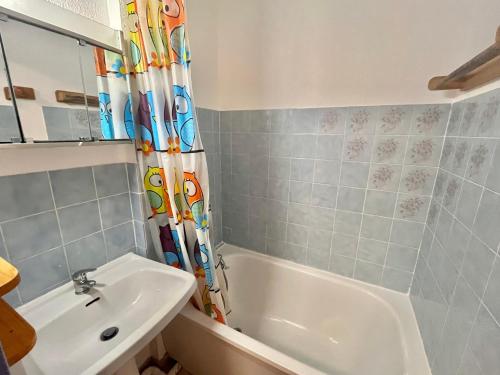 La salle de bains est pourvue d'un lavabo, d'une baignoire et d'un rideau de douche. dans l'établissement Appartement 2 chambres climatisé avec piscine, à 7 min de la plage au Grau-du-Roi - FR-1-716-66, au Grau-du-Roi