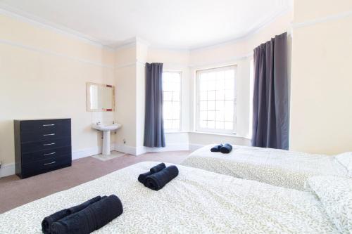 two beds in a bedroom with two large windows at Brookvale Guest House Room 9 in Southampton