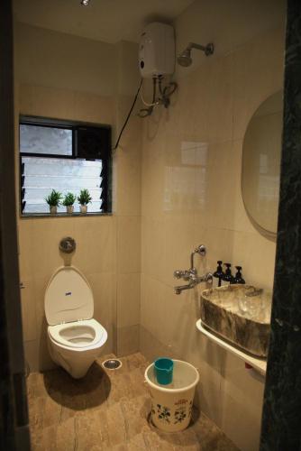 a bathroom with a toilet and a sink and a window at The Bungalow Seven in Lonavala