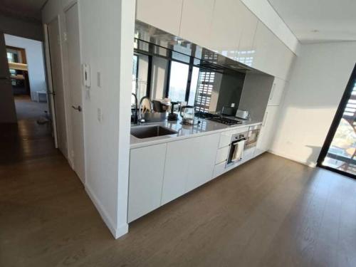 a white kitchen with a sink and a counter at Luxury Apartment St Leonards in Sydney