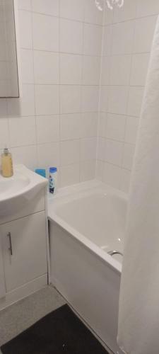 a white bathroom with a tub and a sink at Modern Apartment in Southeast London in Plumstead