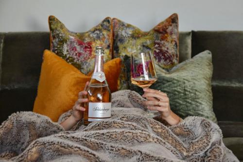 a woman sitting on a couch holding two glasses of wine at Brandlalm Chalets in Gundisch