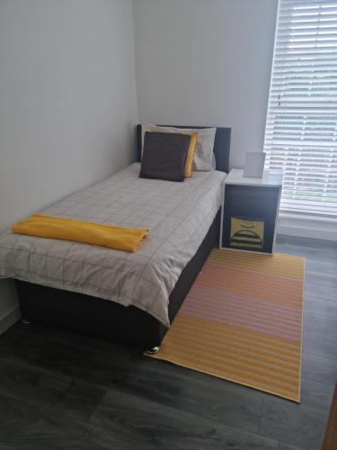 a bedroom with a bed with a yellow blanket at Modern Apartment in Southeast London in Plumstead