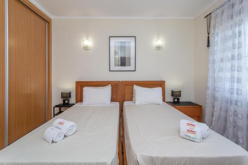 a bedroom with two beds with towels on them at Glenridge Resort By Albufeira Rental in Albufeira