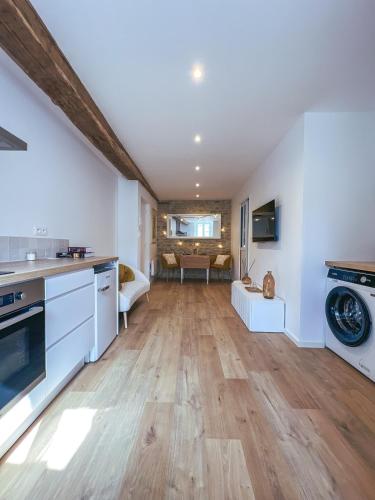 une cuisine et un salon avec des murs blancs et du parquet dans l'établissement Escapade Chambertine au cœur de Gevrey-Chambertin, à Gevrey-Chambertin