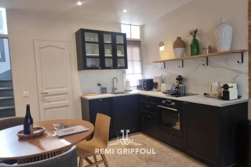 une cuisine avec des armoires noires et une table en bois dans l'établissement La Maison d’Etienne Renovated in 2025! City Center 4 Guests, à Honfleur