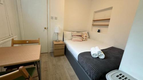 a small room with a bed and a desk and a table at Economic room Sheperds Bush - hotel-like room in London