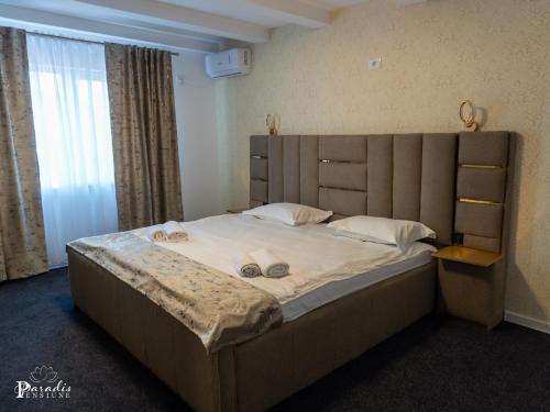 a bedroom with a large bed with a wooden headboard at Pensiunea Paradis Buzias in Buziaş