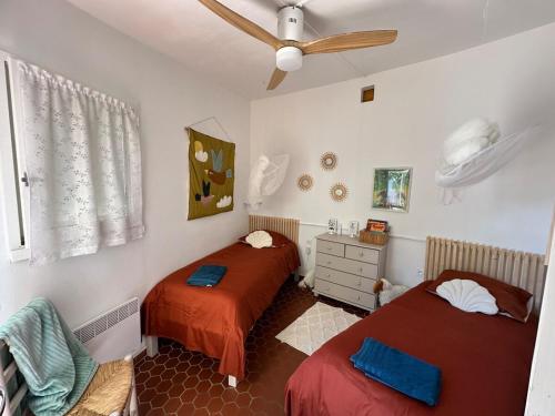 une chambre avec deux lits et un ventilateur de plafond dans l'établissement Maison en bord de mer au Village des Sables, à Torreilles