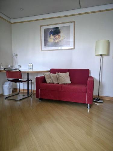 a living room with a red couch and a table at Hotel Vila Mariana Bienal Suites UH 1005 in Sao Paulo