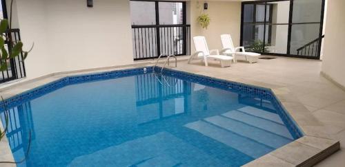 a large blue swimming pool with two chairs in a house at Hotel Vila Mariana Bienal Suites UH 1005 in Sao Paulo
