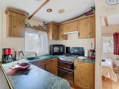 une cuisine avec des armoires en bois et un comptoir dans l'établissement Mobil-Home VI 10 à Vias - La Carabasse - Camping Siblu avec piscine, à Vias