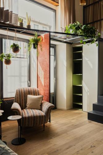 a living room with a chair and a shelf with plants at Bellevue Bocconi Suite in Milan