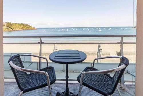 une table et des chaises sur un balcon avec vue sur la plage dans l'établissement Les Pieds Dans L'Eau - Appartment 2 - Vue mer, à Cancale