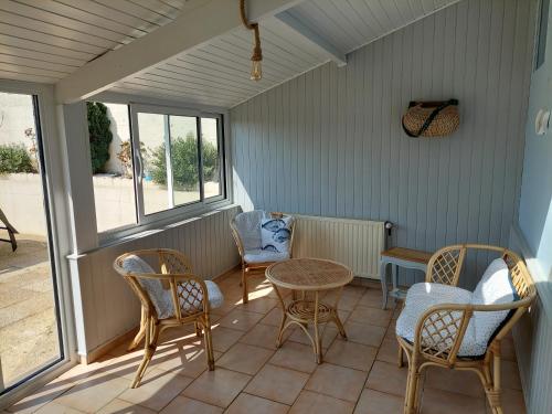 a screened in porch with chairs and a table at Maison cosy & jardin privé Plages à 5 min in Tourville-sur-Sienne
