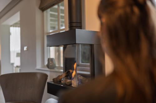 a woman sitting in front of a fireplace at Villa Magnolia in Oostkapelle