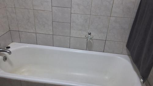 a white bath tub in a bathroom with a shower curtain at SIMICON Guesthouse in Witbank