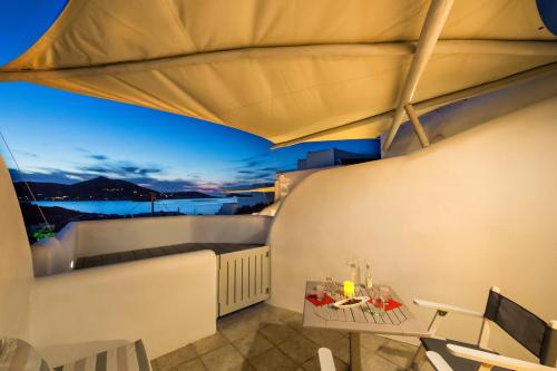 a room with a balcony with a table and chairs at Yades - All Sea VIew Suites - Adults only in Naousa